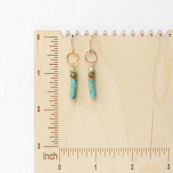 The stacked lana earrings on a wooden ruler for size reference