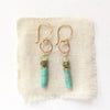 The stacked lana earrings styled on tan linen