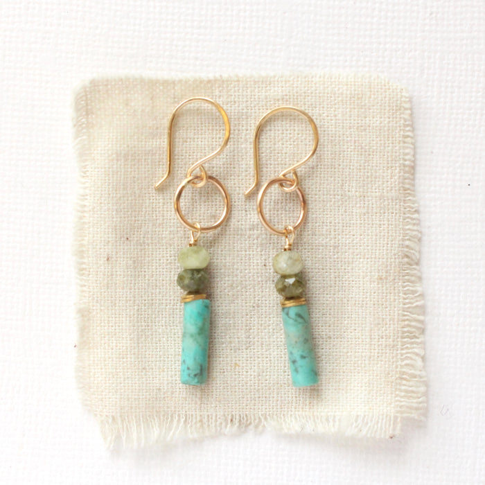 The stacked lana earrings styled on tan linen