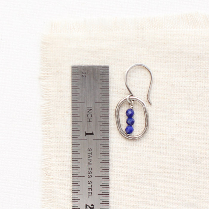 A stacked lapis mini hoop earring next to a ruler for size reference