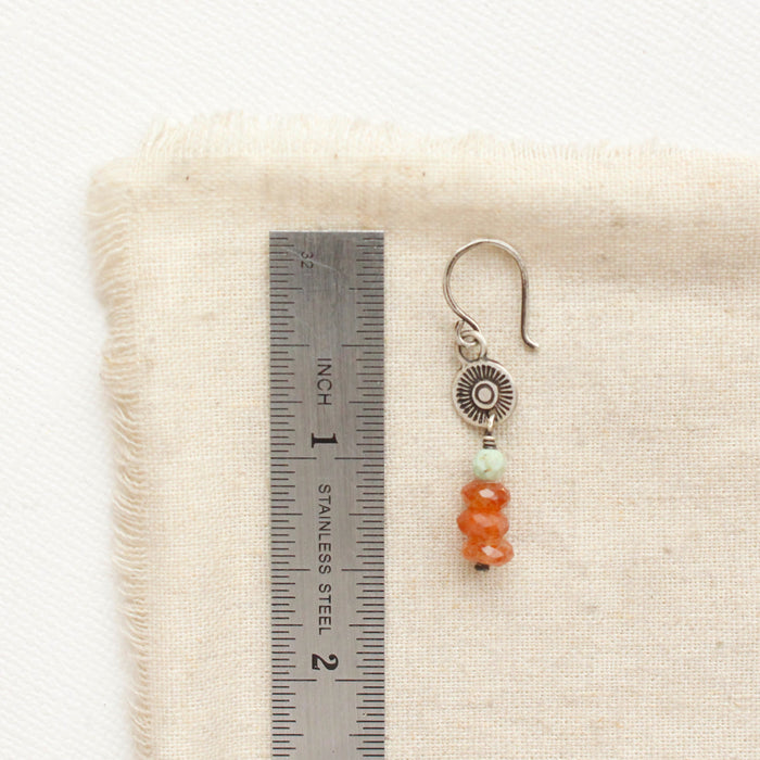 A stacked mesa talara sun earring next to a ruler for size reference