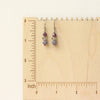 The stacked vinca earrings on a wooden ruler for size reference