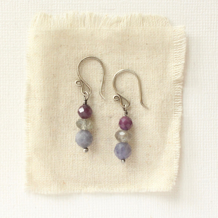 The stacked vinca earrings styled on tan linen