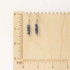 The stacked sapphire earrings on a wooden ruler for size reference