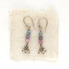 The stacked sapphire dangle earrings styled on tan linen