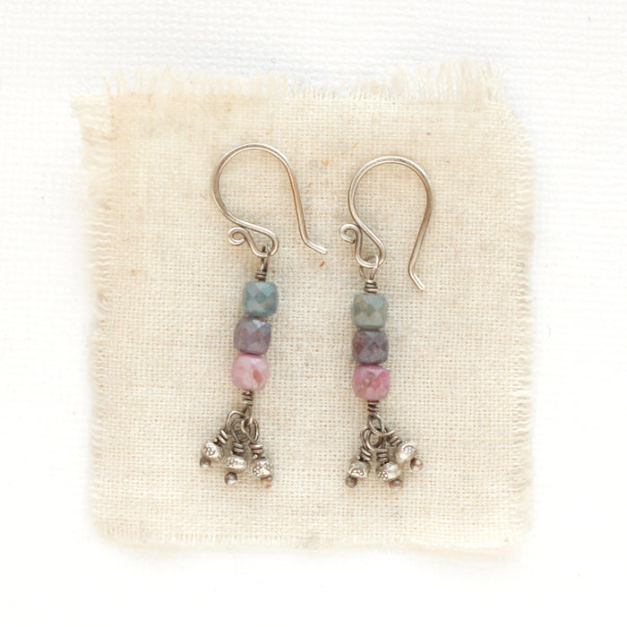 The stacked sapphire dangle earrings styled on tan linen