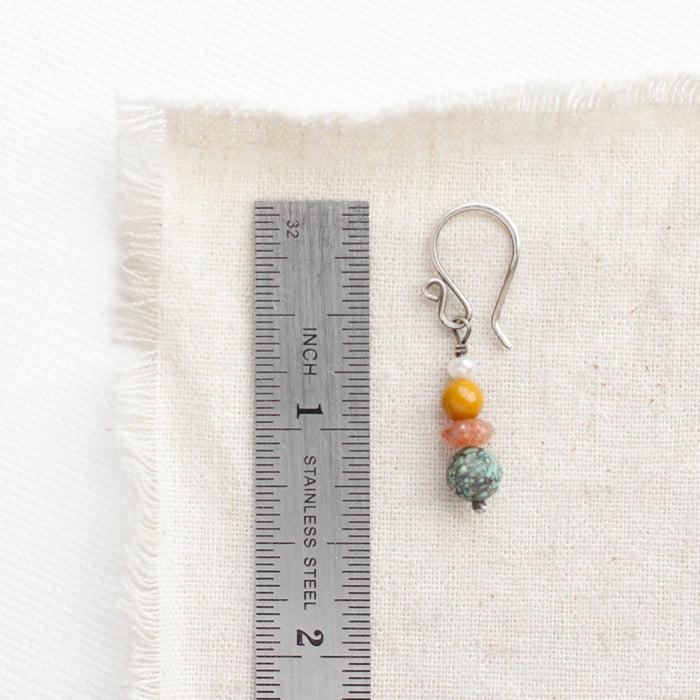 A stacked sunset earring next to a ruler for size reference