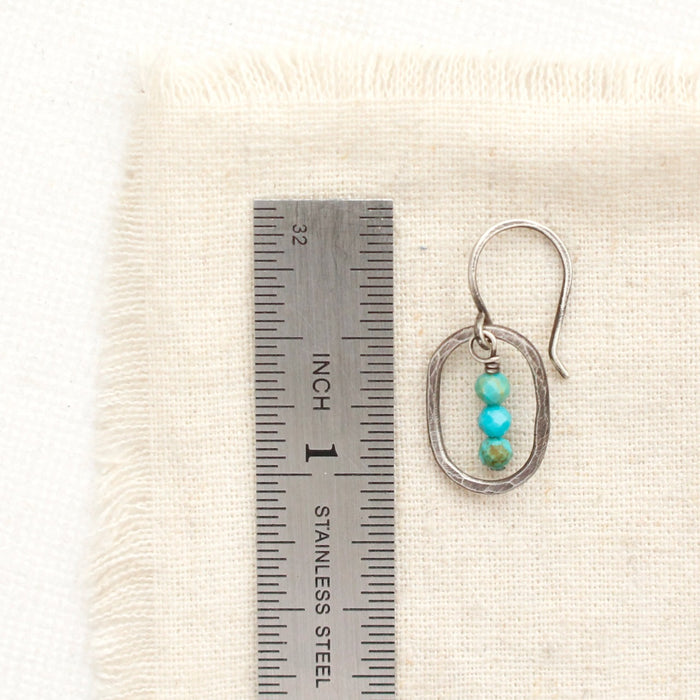 A stacked turquoise mini hoop earring next to a ruler for size reference