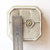 A stamped flower peridot post earring next to a ruler for size reference