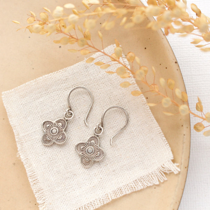 The mini talara earrings styled on a tan plate with linen and dried grass