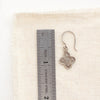 A mini talara earring next to a ruler for size reference
