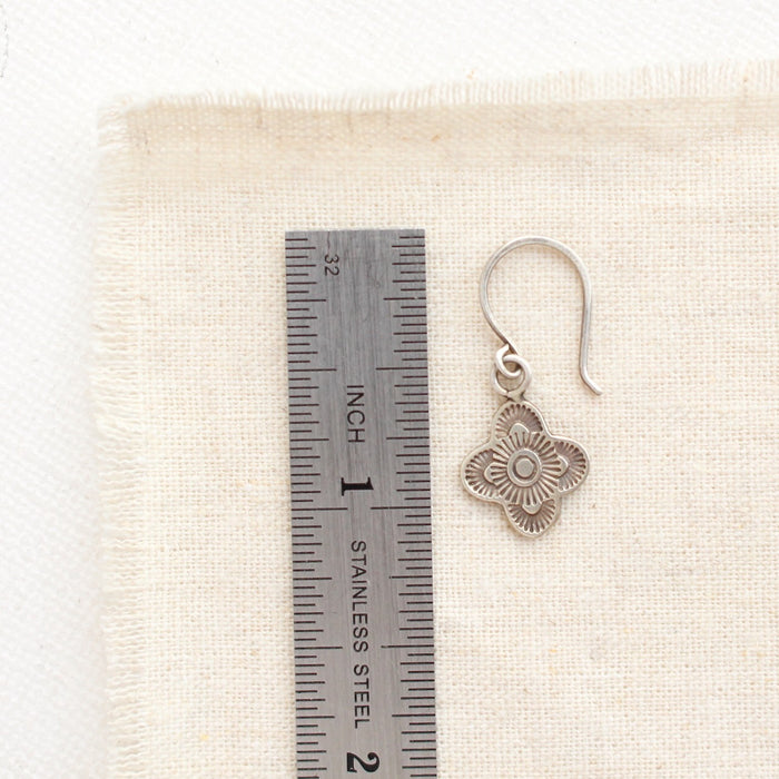 A mini talara earring next to a ruler for size reference