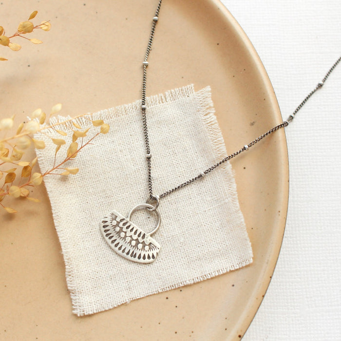 The asmi short loop necklace styled on a tan plate with linen and dried grass