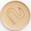 The asmi short loop necklace styled on a tan plate to show the adjustable lobster clasp closure