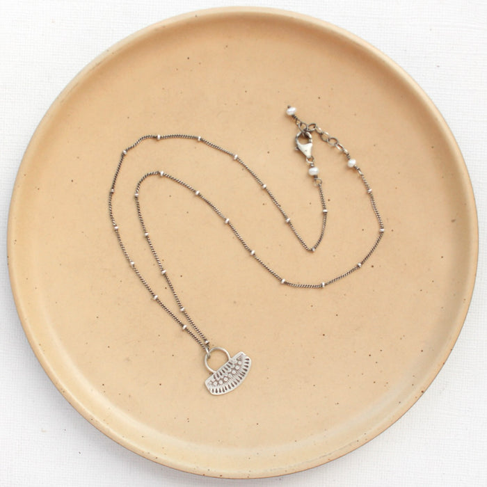The asmi short loop necklace styled on a tan plate to show the adjustable lobster clasp closure