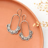 The columbine hoop earrings styled on an orange plate with dried grass
