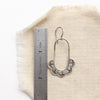 A columbine hoop earring next to a ruler for size reference