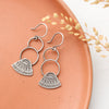The asmi triangle double loop earrings styled on a red plate with dried grass