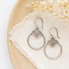The talara hoop earrings styled on a tan plate with linen and dried grass