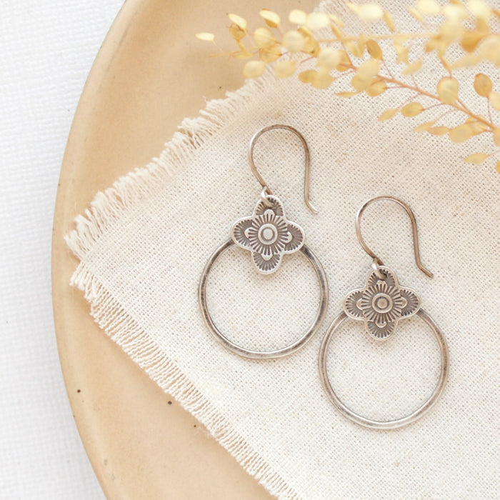 The talara hoop earrings styled on a tan plate with linen and dried grass