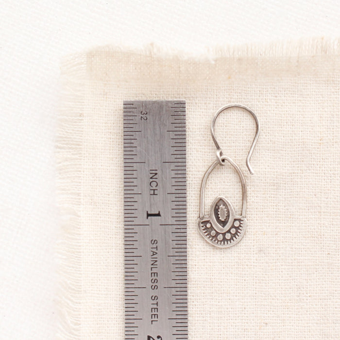 A wanderer hoop earring next to a ruler for size reference
