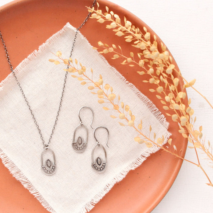 The wanderer hoop earrings styled on an orange plate with the matching necklace