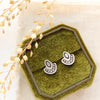 The wanderer post earrings styled on a green velvet box with tan linen and dried grass