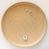 The strawberry bud vintage plate necklace styled on a tan plate to show the adjustable lobster clasp closure