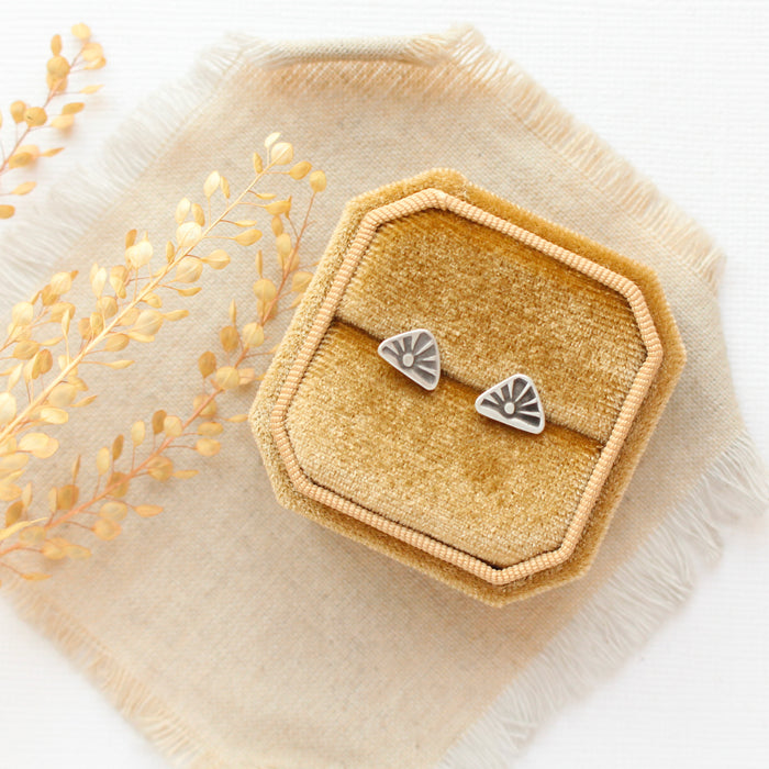 The sun rise post earrings styled on a yellow box with linen and dried grass