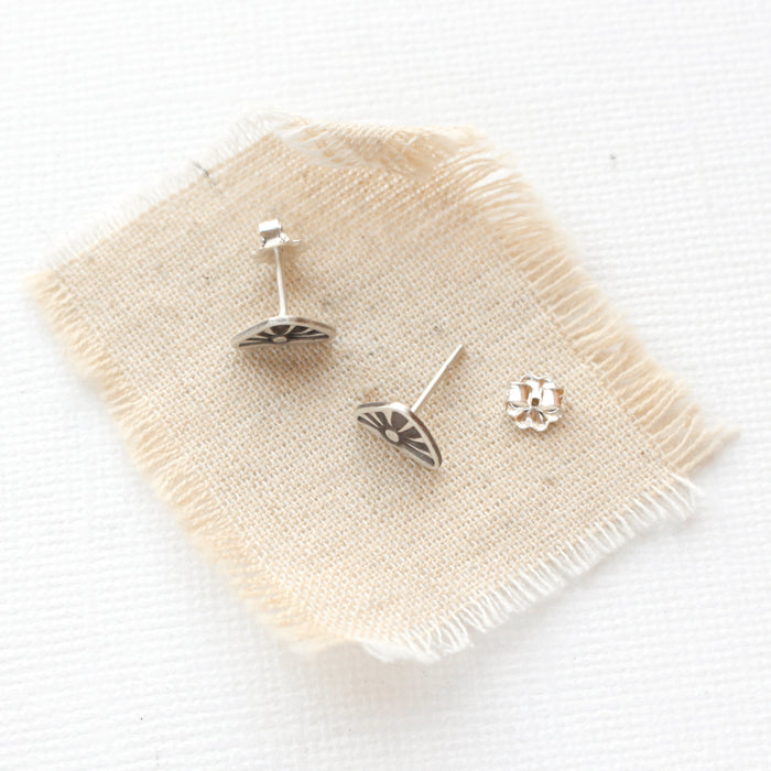 The sun rise post earrings styled on tan linen to show the butterfly earbacks