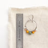 A sunset hoop earring next to a ruler for size reference