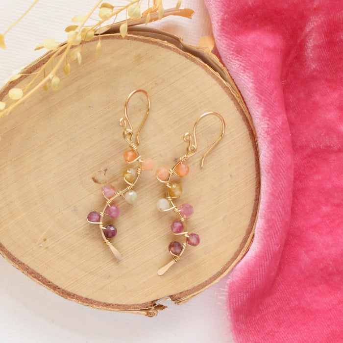The sunset vine earrings styled on wood with pink velvet and dried grass