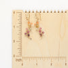 The sunset vine earrings on a wooden ruler for size reference