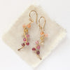 The sunset vine earrings styled on tan linen