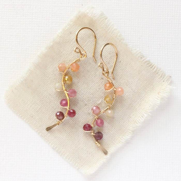 The sunset vine earrings styled on tan linen