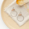 The sunstone halo hoops styled on a tan plate with linen and a crystal