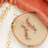 The sunstone wrapped silver vine earrings styled on wood with coral velvet and dried grass
