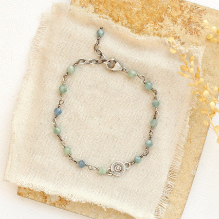 The talara sun kyanite bracelet styled on tan linen with a tan rock and dried grass
