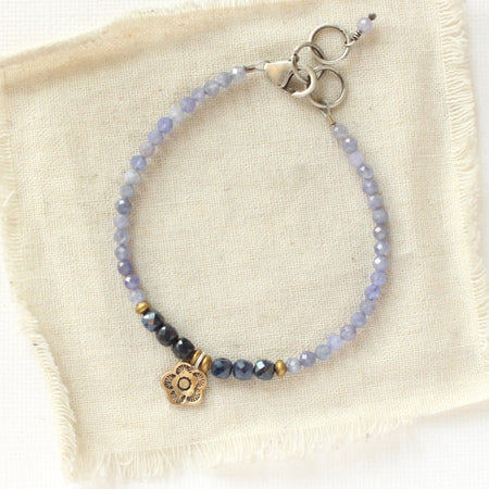 The bronze mini cactus flower vinca bracelet styled on tan linen