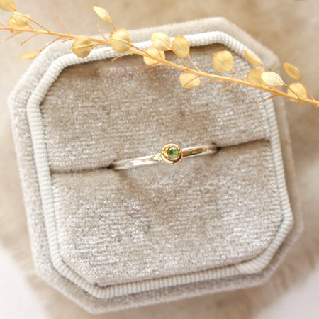 The green tsavorite garnet mixed metal stacked ring styled on a beige velvet ring box with tan linen and dried grass