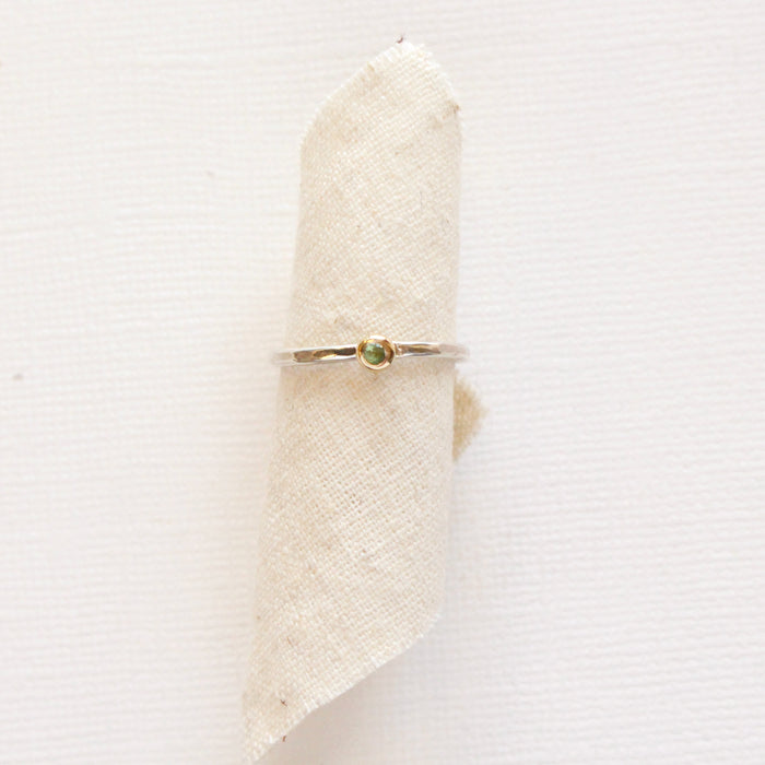 The green tsavorite mixed metal stacking ring styled on tan linen