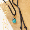 The turquoise drop adjustable leather necklace styled on tan leather with dried grass