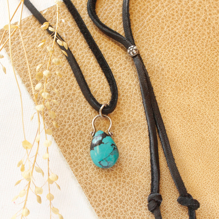 The turquoise drop adjustable leather necklace styled on tan leather with dried grass