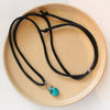 The turquoise drop adjustable leather necklace styled on a tan plate to show the whole necklace and silver slider