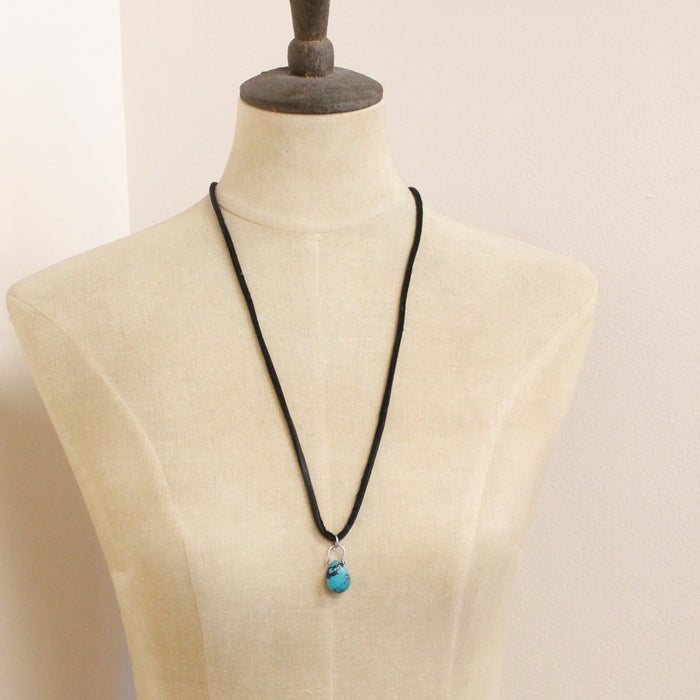 A mannequin wearing the turquoise drop adjustable leather necklace