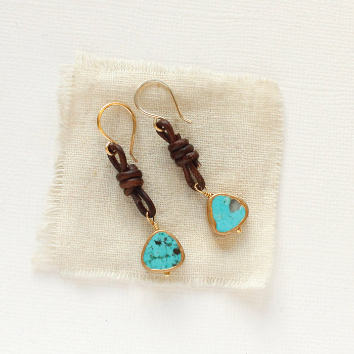 The turquoise and leather earrings styled on tan linen
