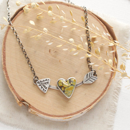 The turquoise cupid's arrow necklace styled on wood with linen and dried grass