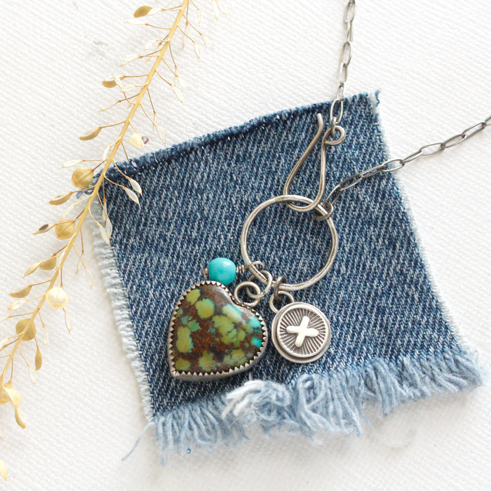The royston turquoise charm necklace styled on blue linen with dried grass