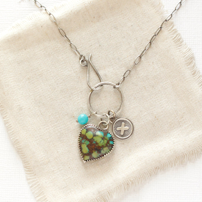 The royston turquoise heart charm necklace styled on tan linen