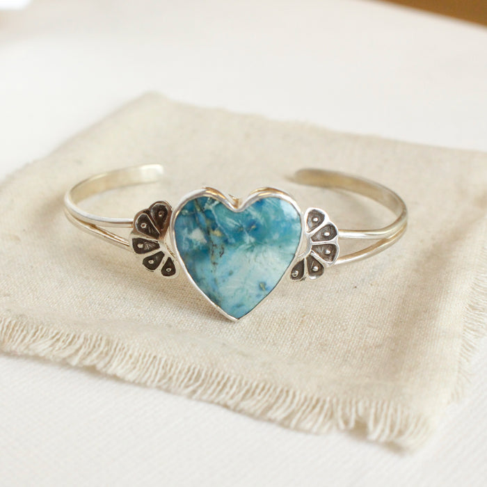 The turquoise heart cuff bracelet styled on tan linen